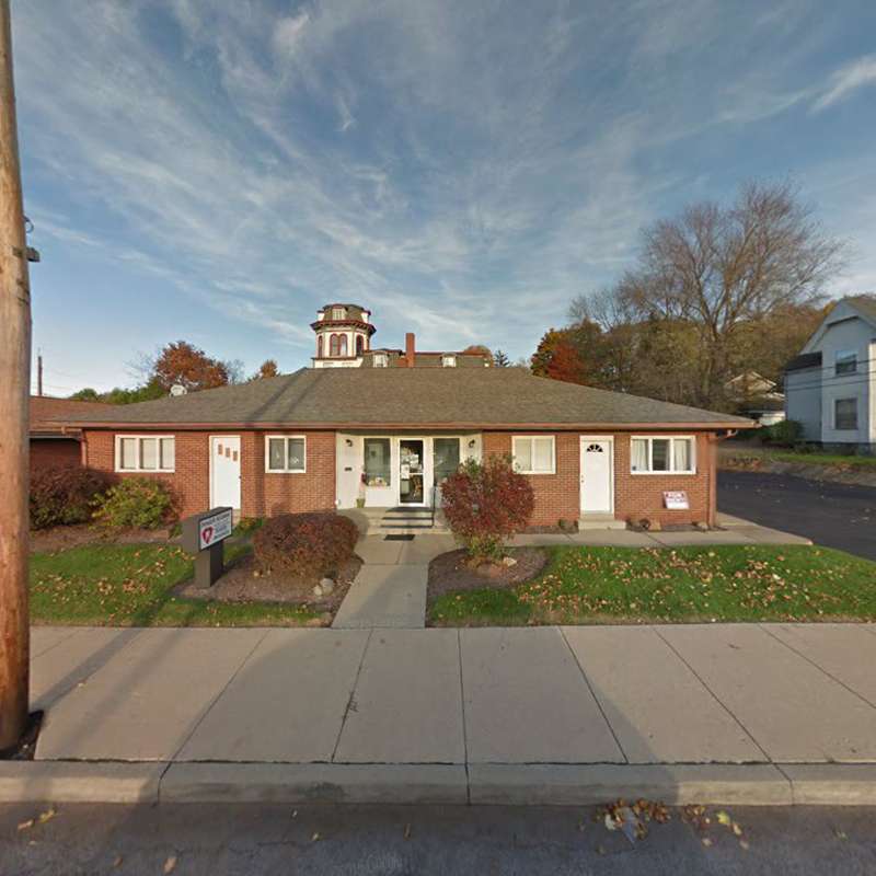 Red brick dental office building with entrance and landscaping on residential street.