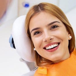 Smiling young woman in dental chair during examination at modern dental office