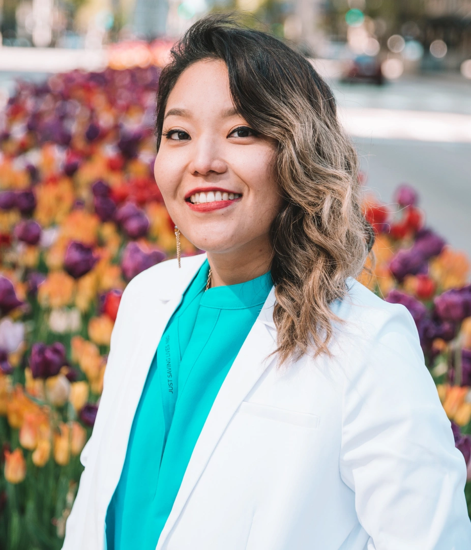 Professional outdoor headshot of Dr. Ariee Jung smiling in a white lab coat.