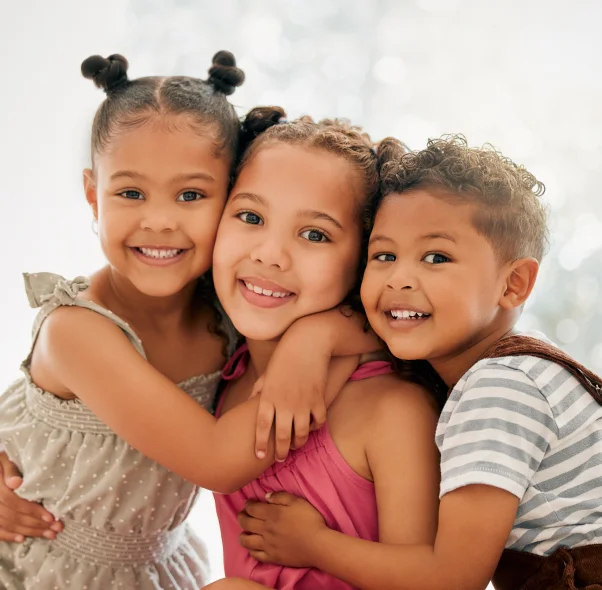 Three smiling children hugging at Lombardi Dental, a kid-friendly dentist in Sharpsville, PA